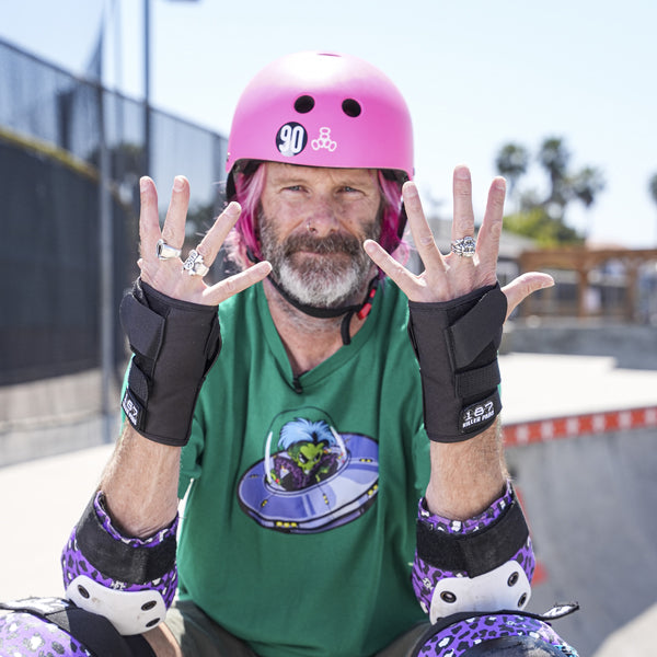 Kevin Staab wearing a pink helmet and 187 Killer pads protective skate gear, at a skate park.